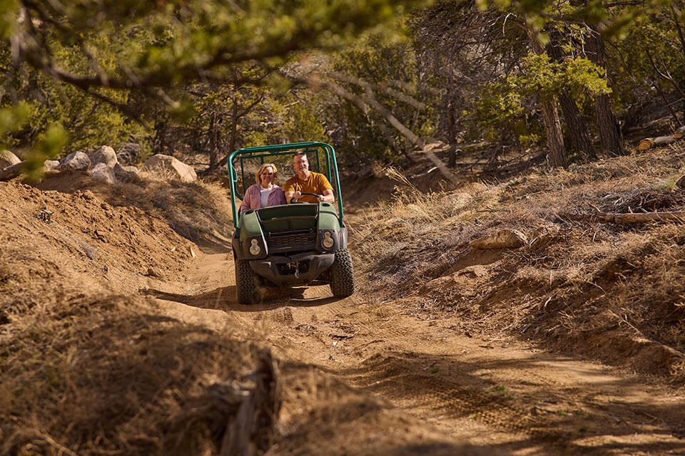 Couple rides ATV in rural wood setting in Colorado