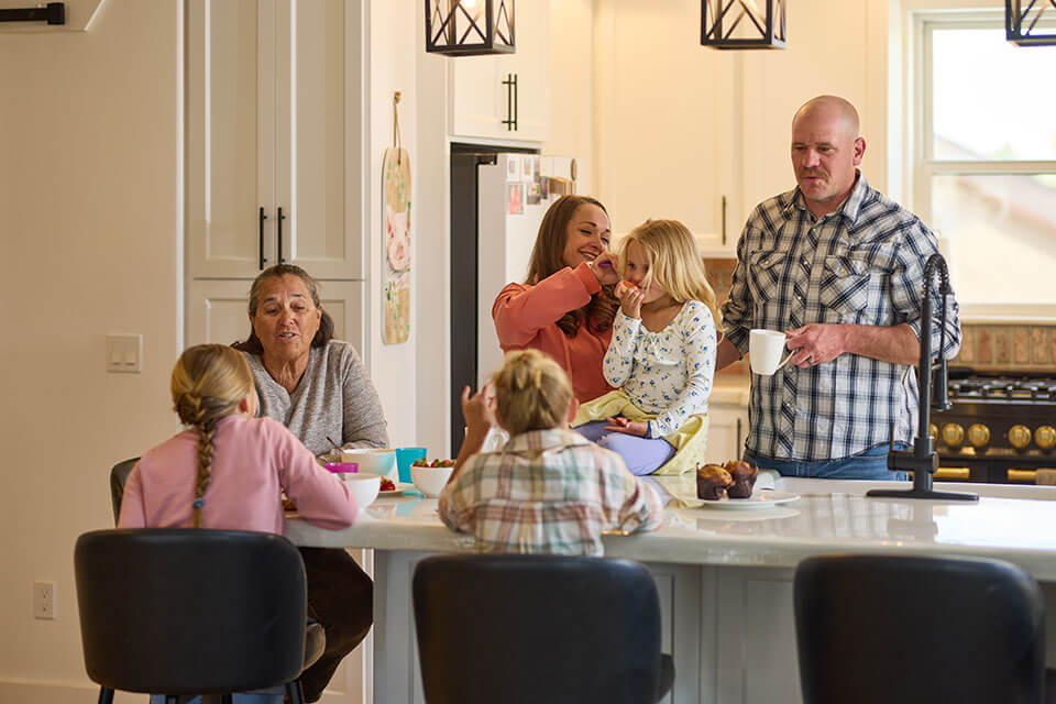 A family happily gathers and interacts around a spacious modern kitchen island.